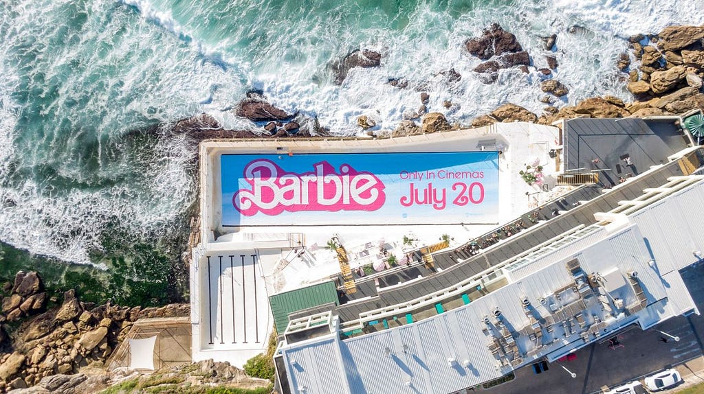 Aerial view of the Bondi Icebergs Swimming Club in Sydney, Australia — with the bottom of the pool replaced with a Barbie movie logo and release date.