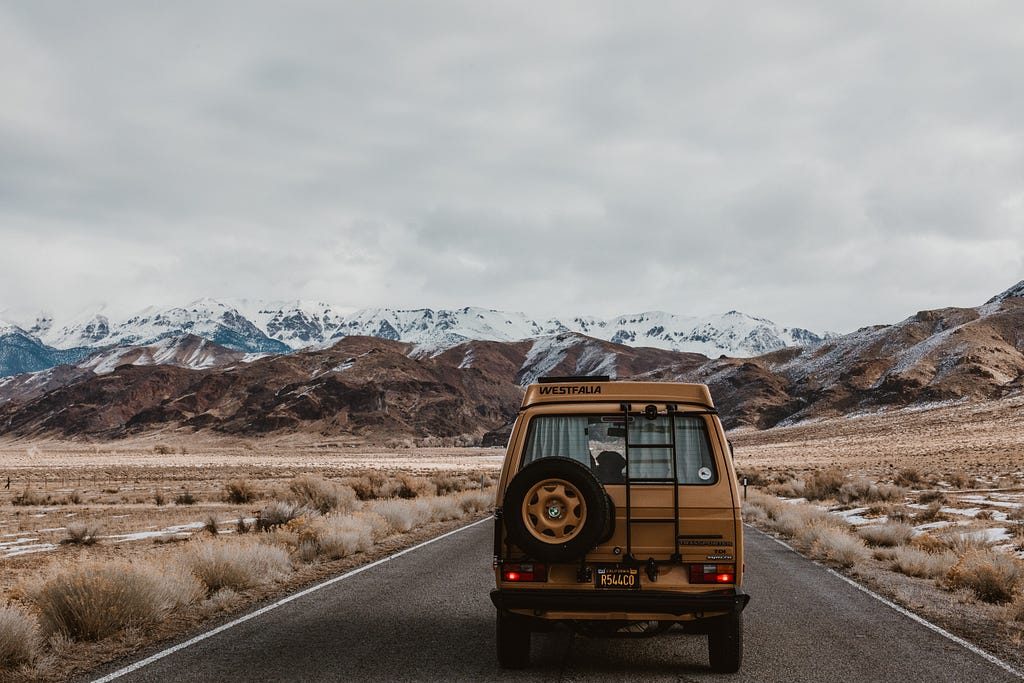 Foto de una camioneta transitando una ruta con una montaña en el horizonte de paje victoria en Unsplash