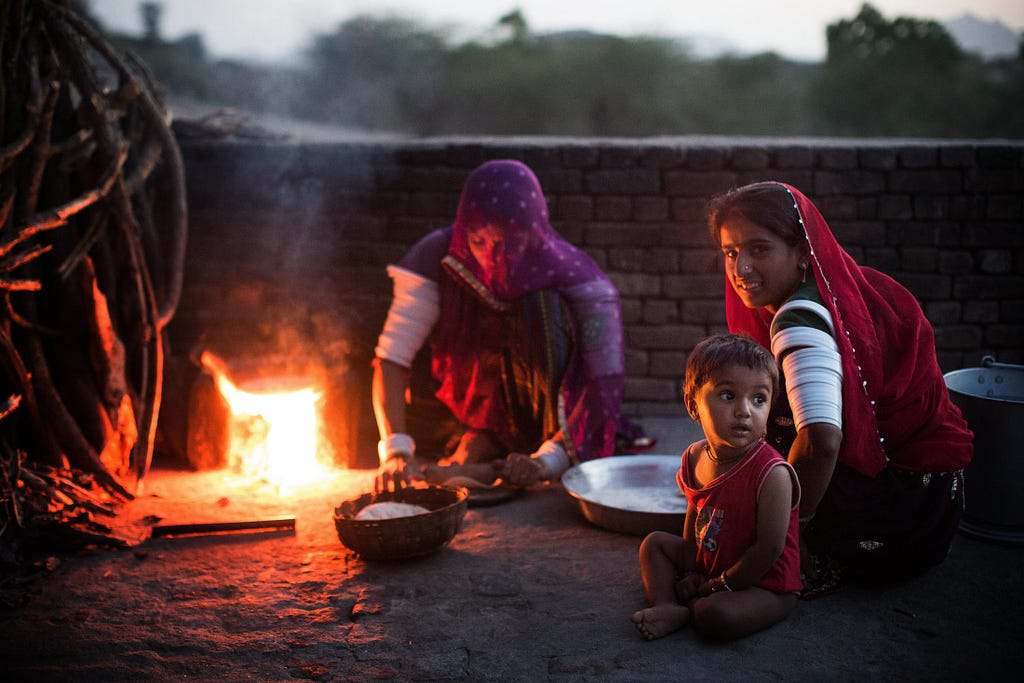 Mantra Ram and her sister roll out dough to bake chapati on a wood-fired chulha, or clay stove, for the evening meal. 