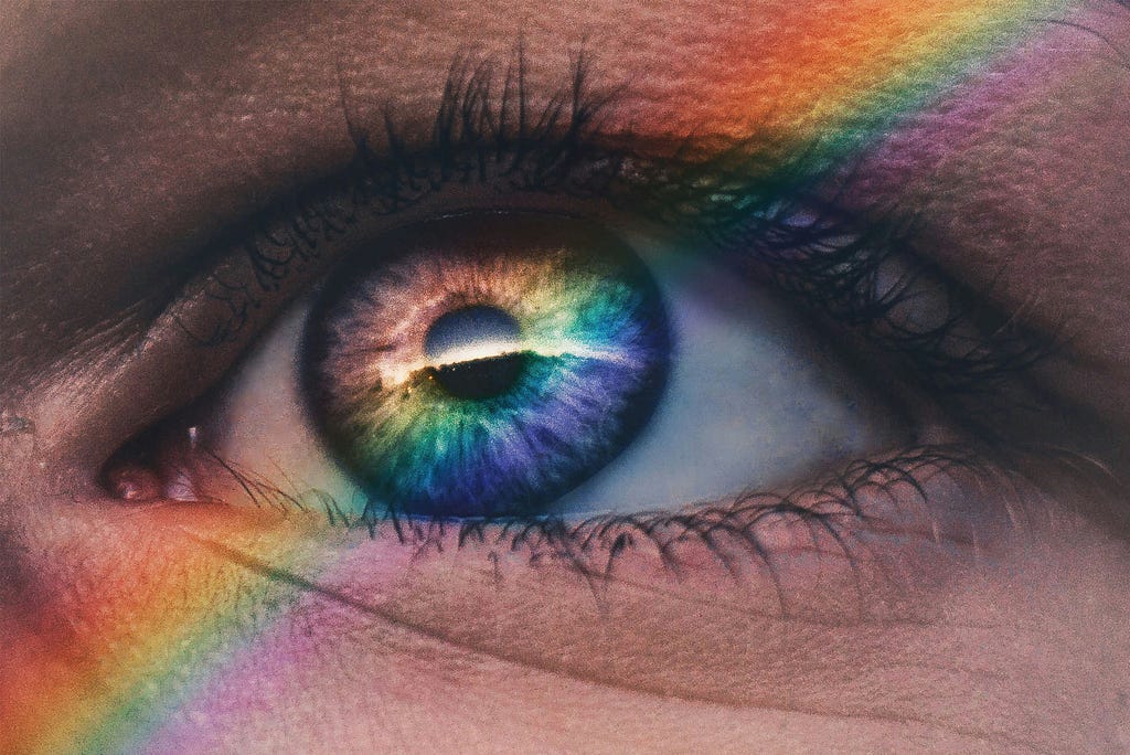 close-up of eye with rainbow light at an angle across it