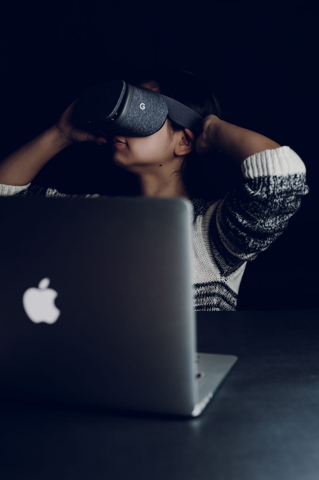 Lady wearing a VR headset with a laptop in front of her