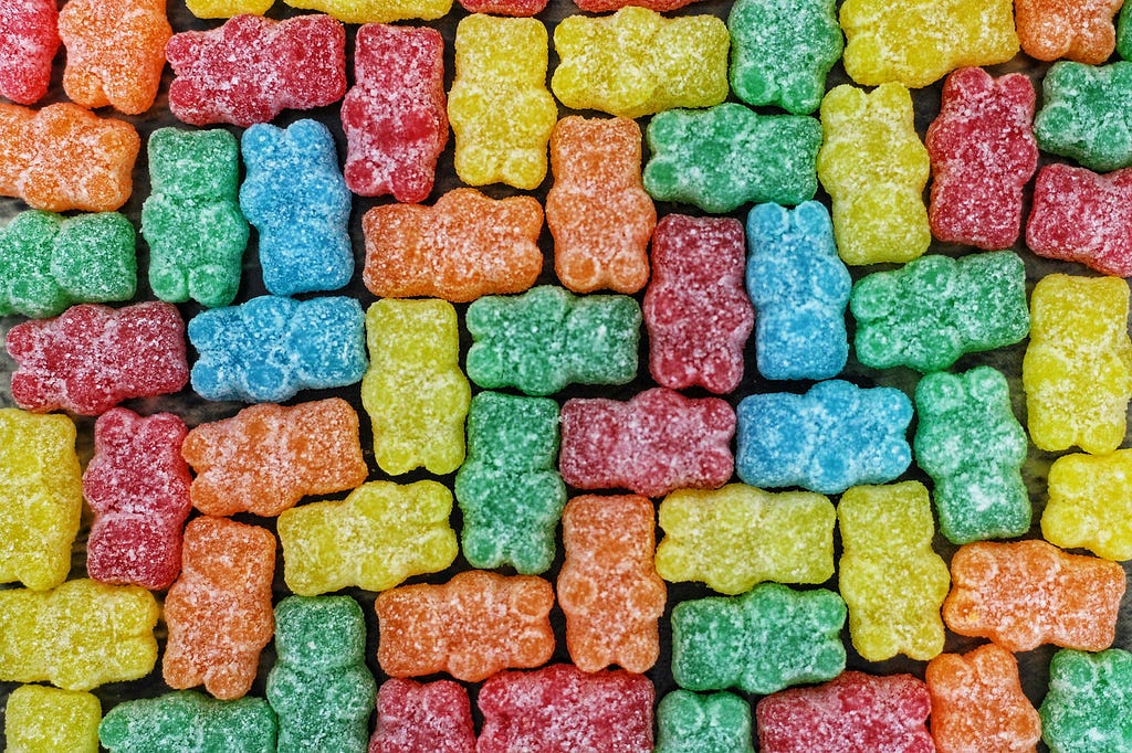 An array of multicoloured gummy bears laying stacked neatly in a pattern