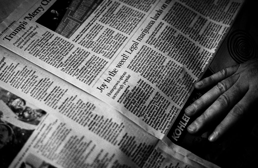 a black and white photo of a newspaper with a hand skimming over it