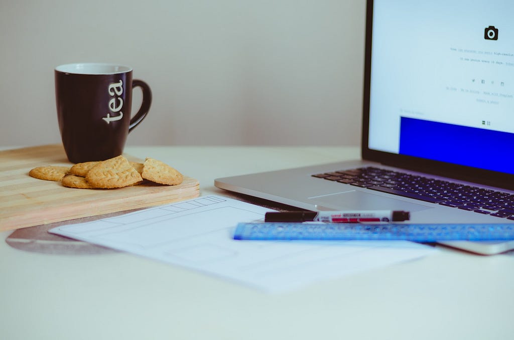 A mug of tea sits beside a laptop