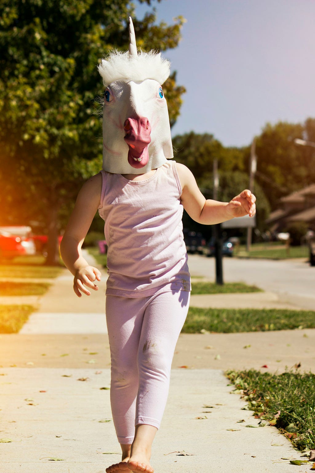 A person walking down the street with a big unicorn mask