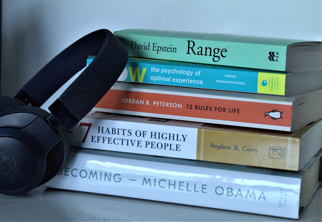 A picture of self-help books and a black headphone.