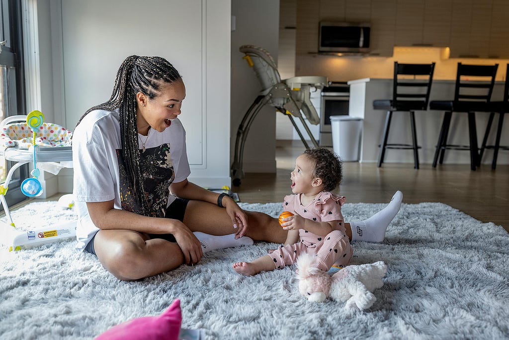 Napheesa Collier plays with her daughter on the floor of her home.