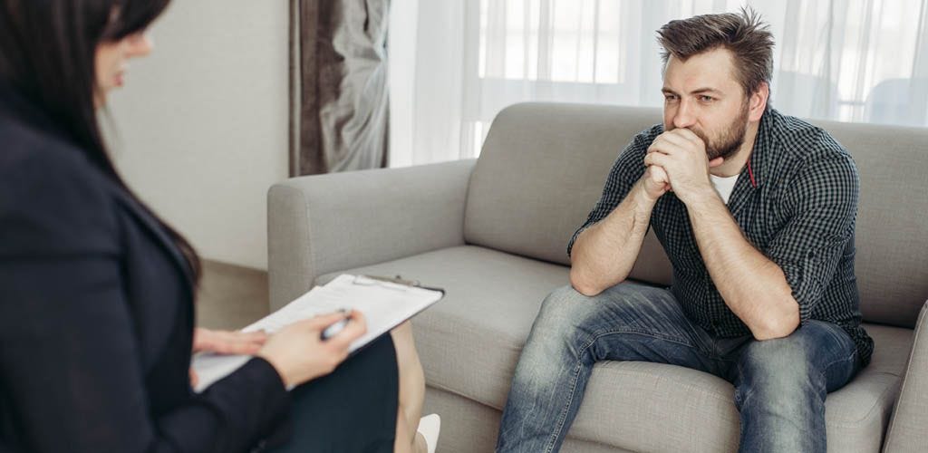 Man sitting on couch speaking with psychologist