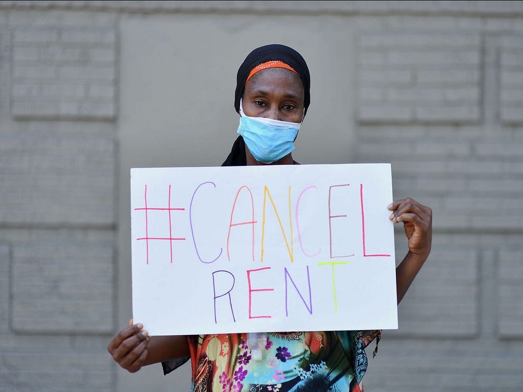 An individual holding a #CancelRent sign.