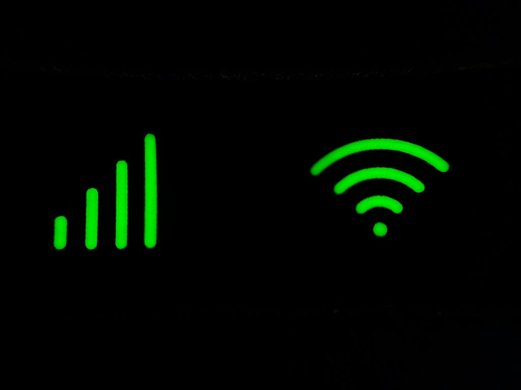 Neon green images of a wifi signal and mobile phone reception bars against a black background.