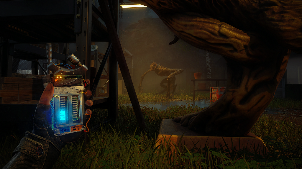 First-person POV with the left hand out holding some sort of detection device, one of the meters lit up half way with blue light. The player is crouched in the grass behind some structures. There is a creature in the distance, long front legs that come down into almost blades, and flat hind legs.