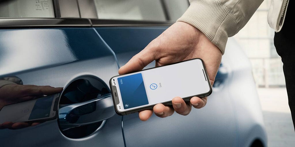 Person holding a smartphone next to the door of a car, in order to unlock the vehicle.