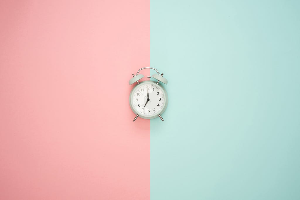 An alarm clock with a pink & green backround.