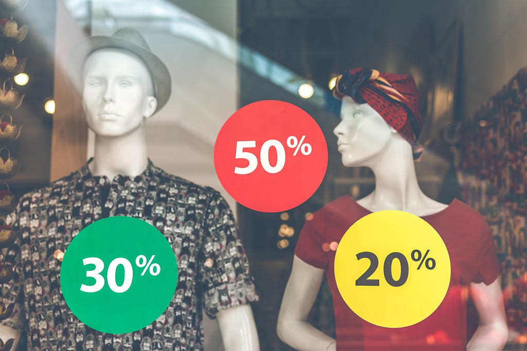 manikins model clothes with discount tags in store window