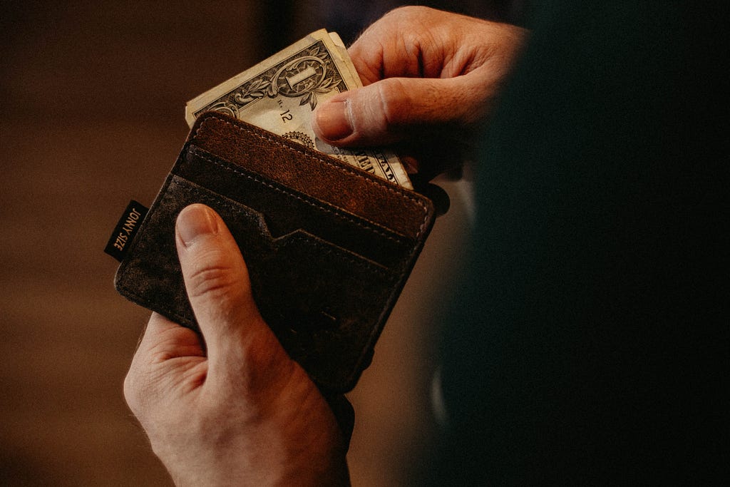 a picture of hands pulling bills out of a wallet