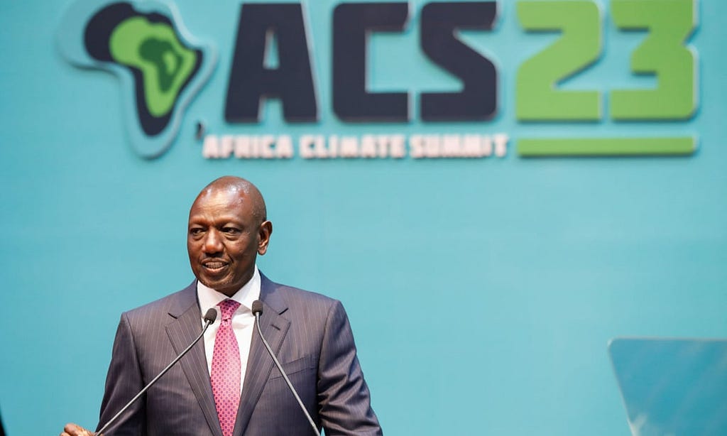The picture depicts Kenyan President, William Ruto, standing at a podium. Behind him, is a sign that reads “ACS 23: Africa Climate Summit”