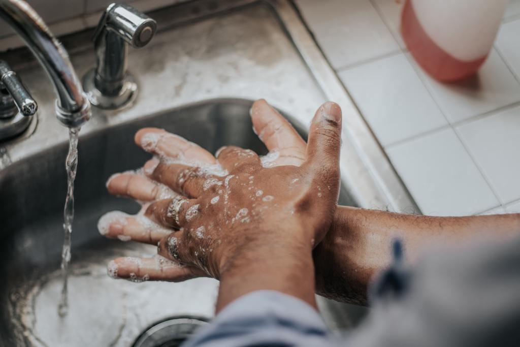 Person washing hands with soap and water at a sink