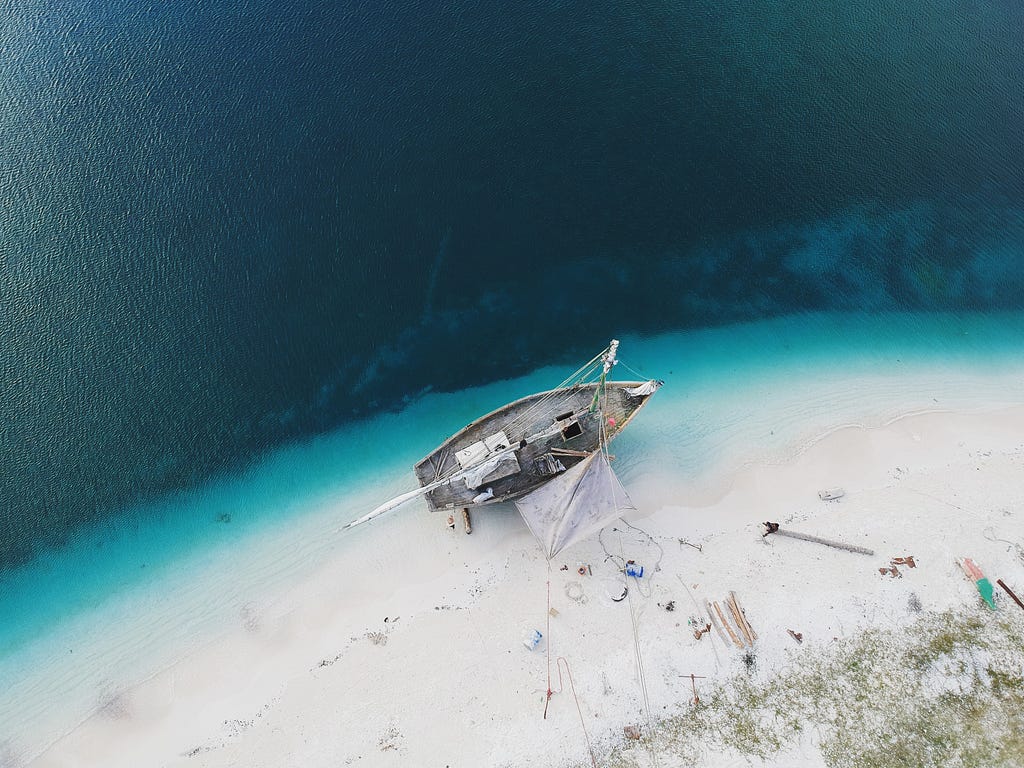 Aerial photo of a ship on a beach being worked on.