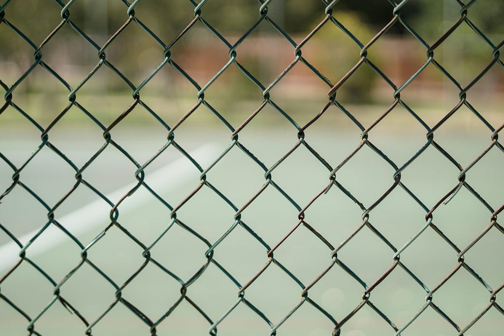 Photo of a diamond pattern fence mesh with a blurry background