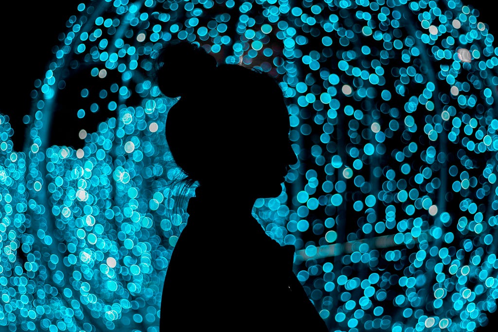 woman standing in the dark infront of blue lights