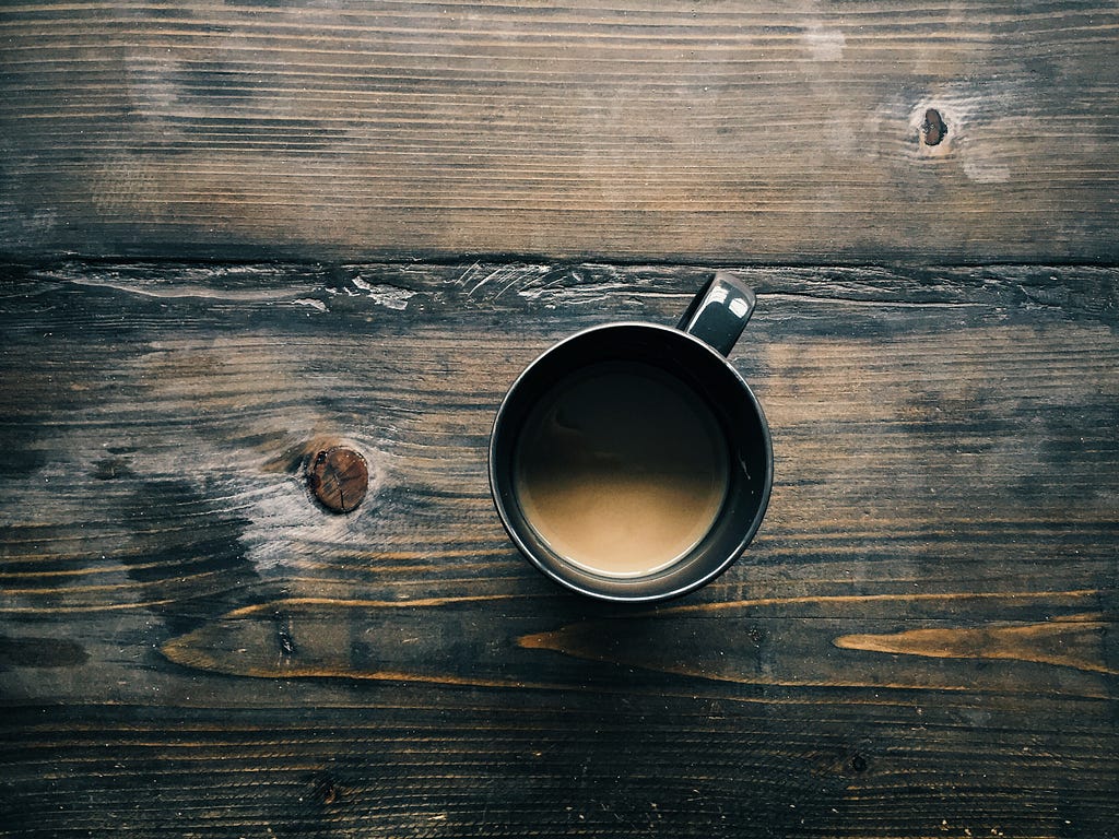 espresso coffee in black mug sitting on wooden bench