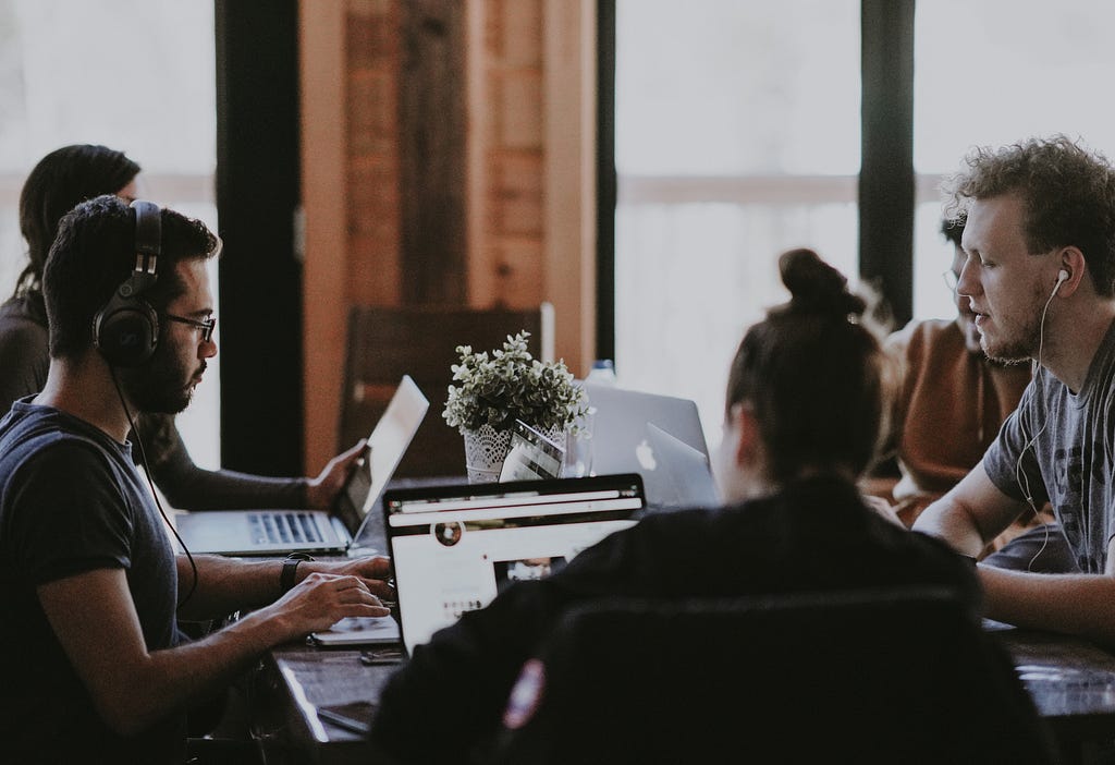 A group of 5 people working together on laptops.