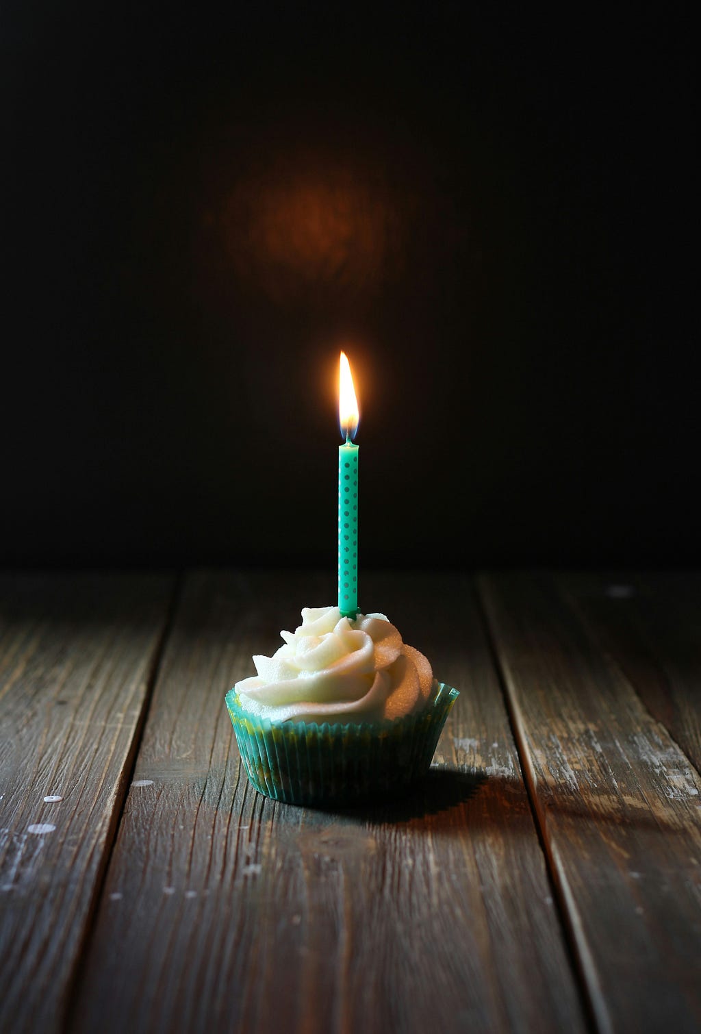 A single turquoise candle on top of a cupcake.