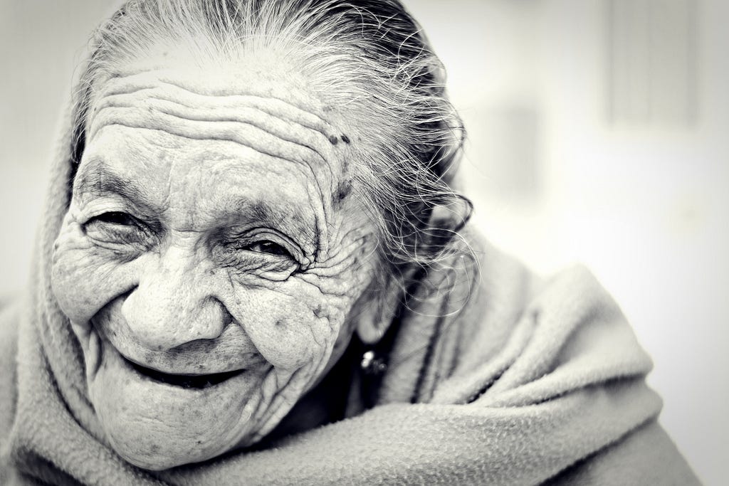 Black and white photo of a smiling, toothless elderly woman.