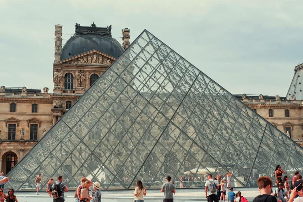 A group of people standing in front of the louvre pyramid.