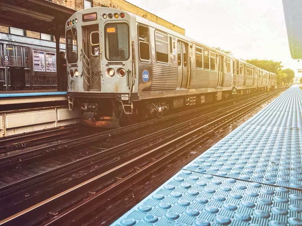 A train is coming down the tracks at a station.