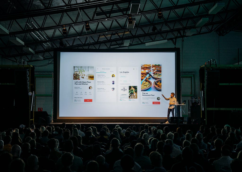 A speaker presenting at a design conference in front of an audience