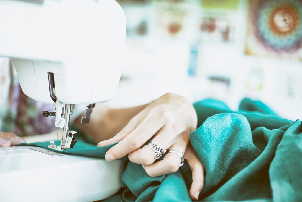 A person sewing fabric using a domestic sewing machine.