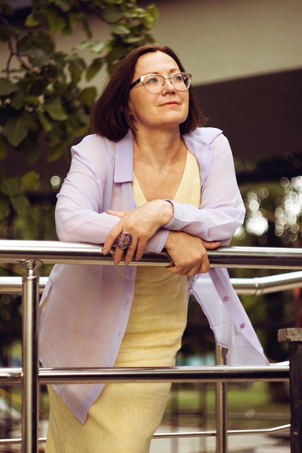 An attractive well dressed middle-aged woman leaning against a rail