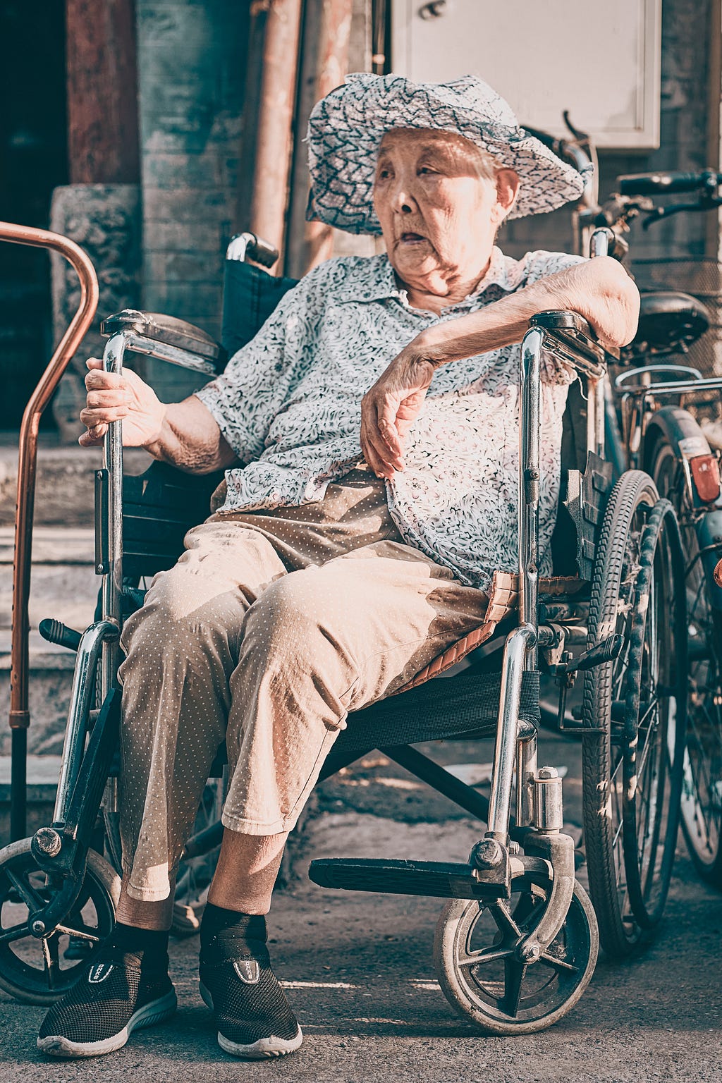 Photo of an elderly woman in a wheelchair with high armrests.