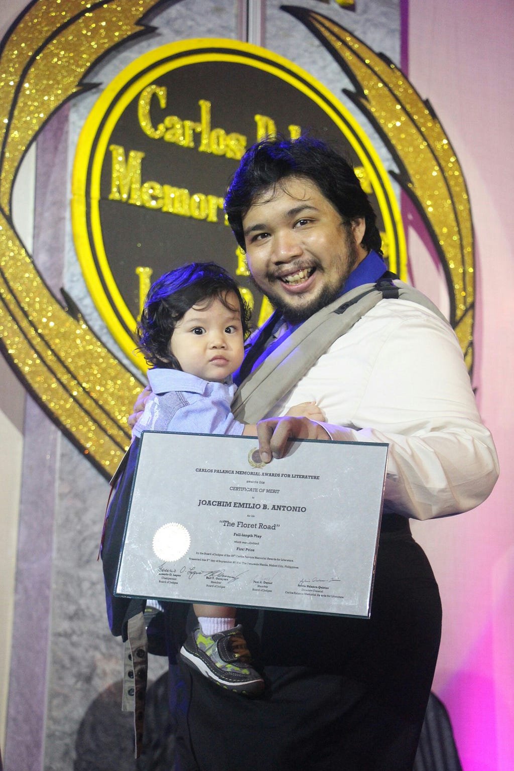 Joem Antonio and his baby boy hold up the first prize certificate