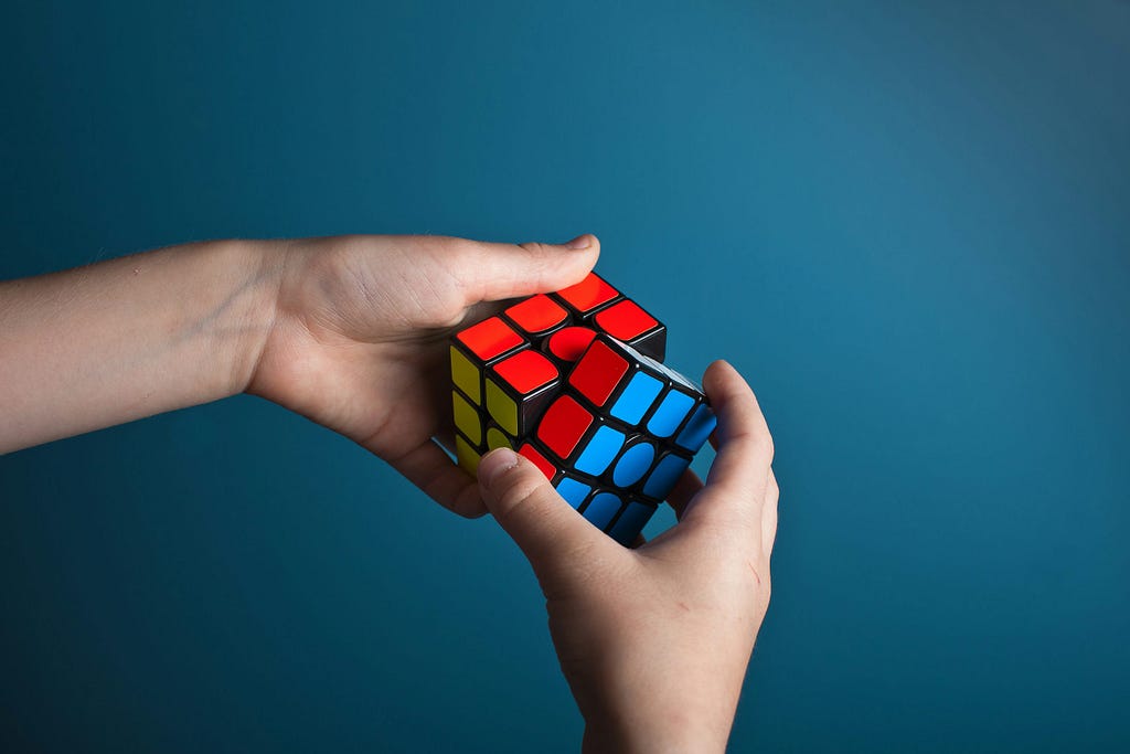 A person solving a Rubik cube with both hands.