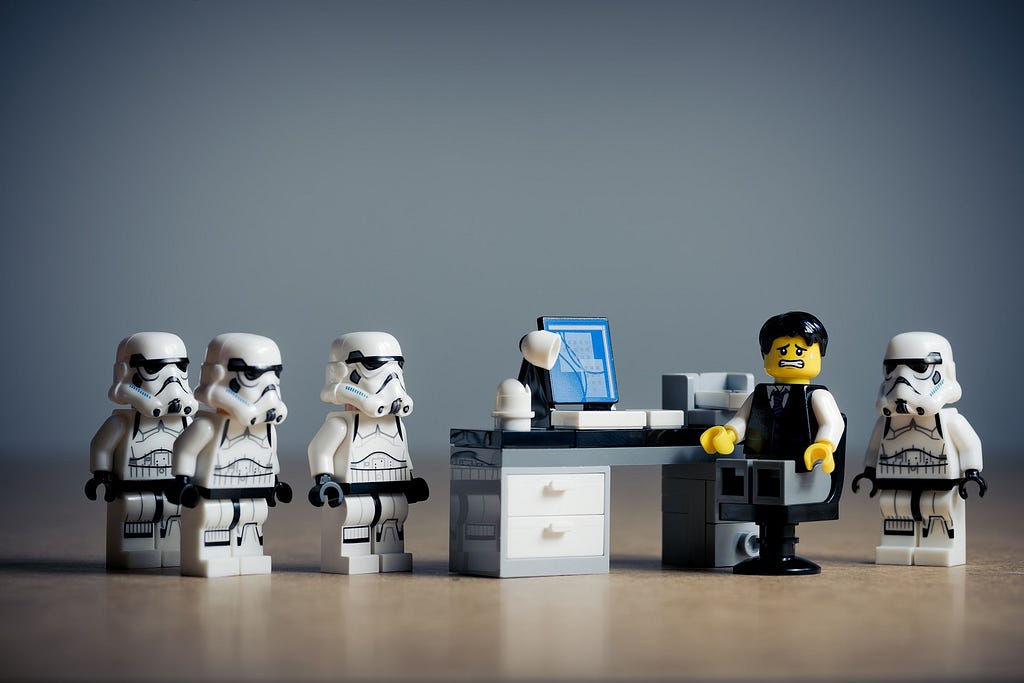 Some Lego Star Wars’ Clone Troopers threatening an employee at his desk.