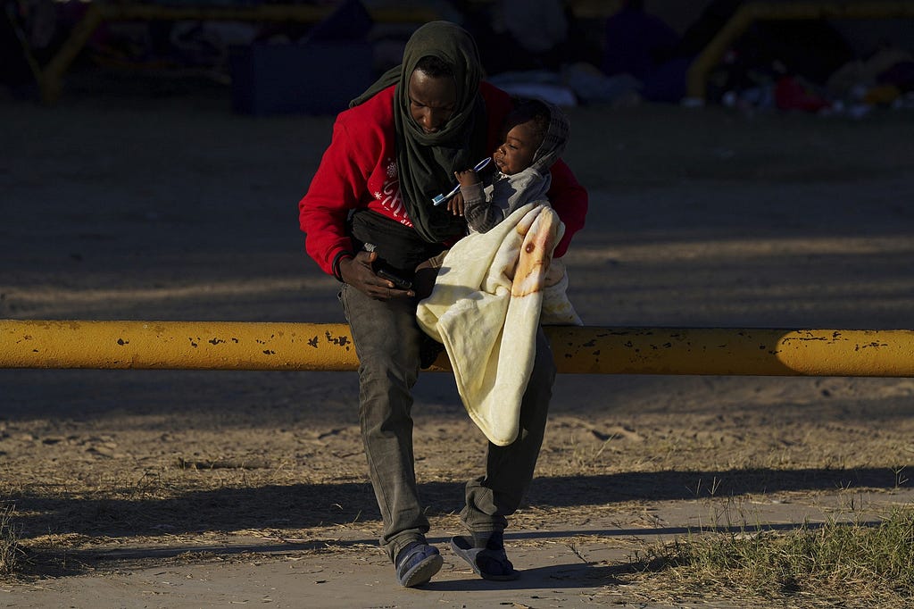 An Haitian migrant holds his baby as he uses a cellphone at an improvised refugee shelter in Ciudad Acuna, Mexico, Friday, Sept. 24, 2021, across the Rio Grand river from Del Rio, Texas. (AP Photo/Fernando Llano)