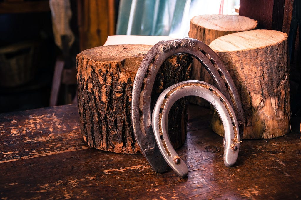 2 horseshoes leaned against 3 wood logs