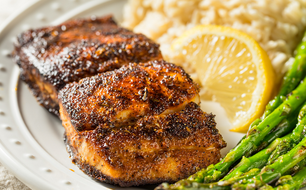 Plate with Blackened Tilapia, mash potatoes, steamed asparagus, and a lemon wedge.