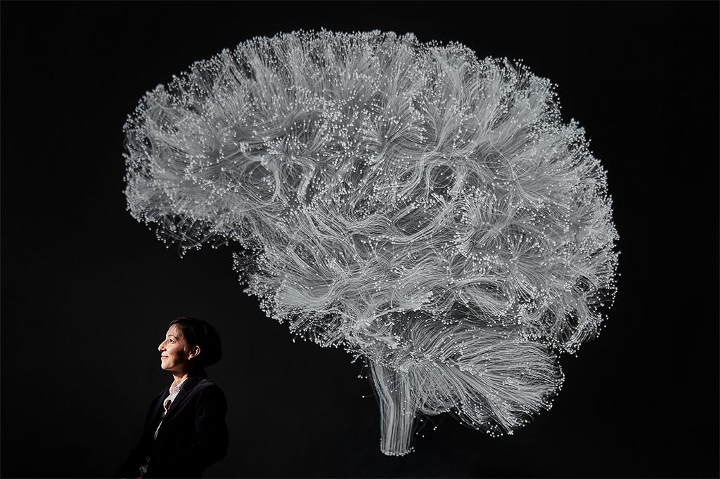Professor Danielle Bassett poses under a black-and-white illustration of the brains complex structural network.