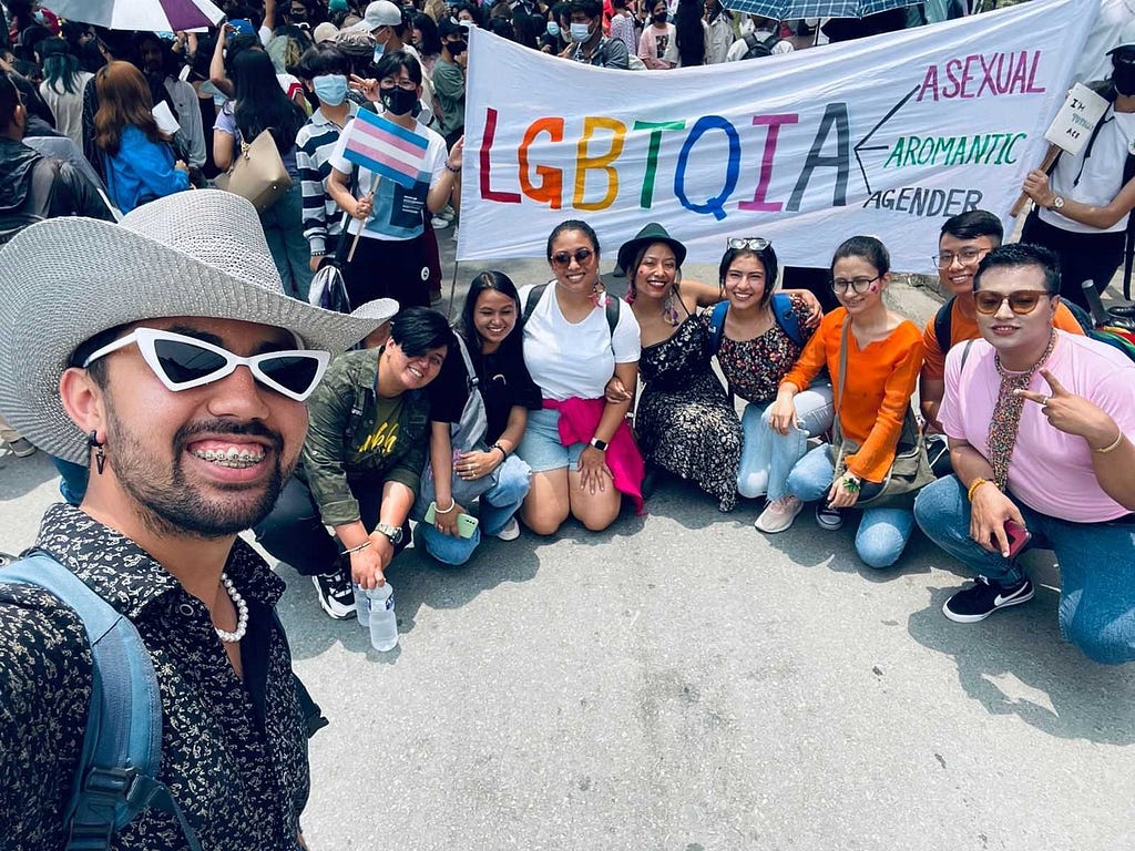 A picture of a number of people at the parade including my colleagues in front of a flag that says LGBTQIA where A stands for Asexual, Aromantic, and Agender.