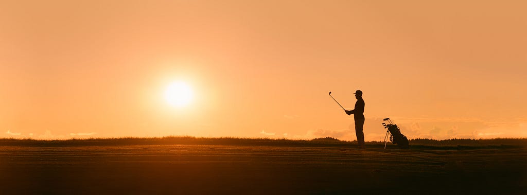 A silhouetted golfer, mentally preparing to tee off at sunset.