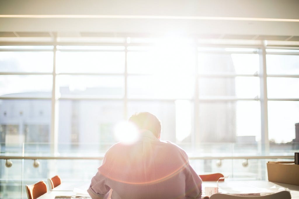 man sitting in front of sunny window in office