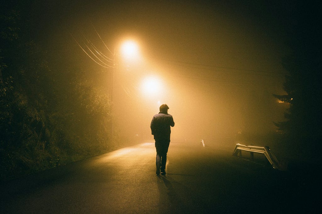 A man standing in fog under the street lights