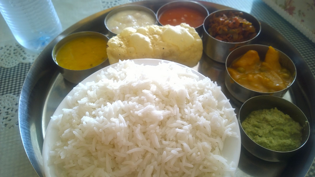 A photograph of a ‘thali’ with a large plate with many small bowls for dal (pulses), curries, sabzis (dry vegetable dishes), and dahi (curd).