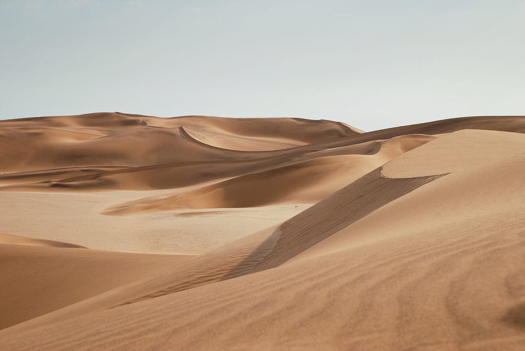 A wide expanse of dry sand in a desert.