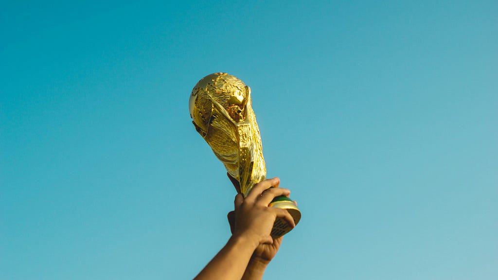 gold soccer trophy against a solid blue sky background