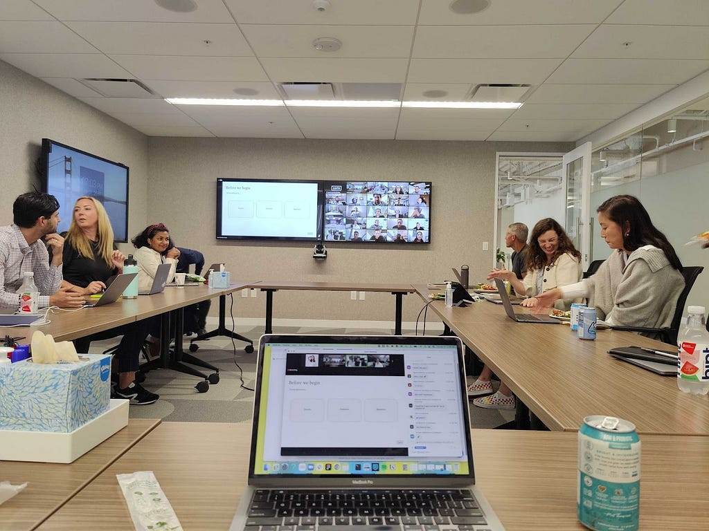 view of a full meeting room with a meeting on the tv