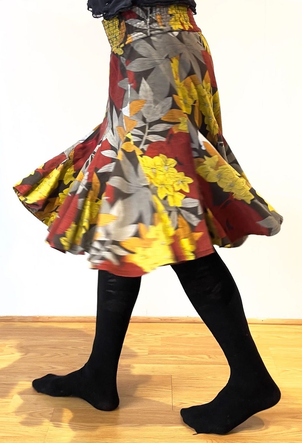 Spinning with red/yellow/grey/orange flower patterned skirt, and black tights.